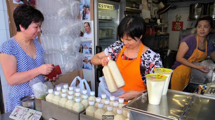 یک زن در هنگ‌کنگ شیر سویا می‌خرد. 