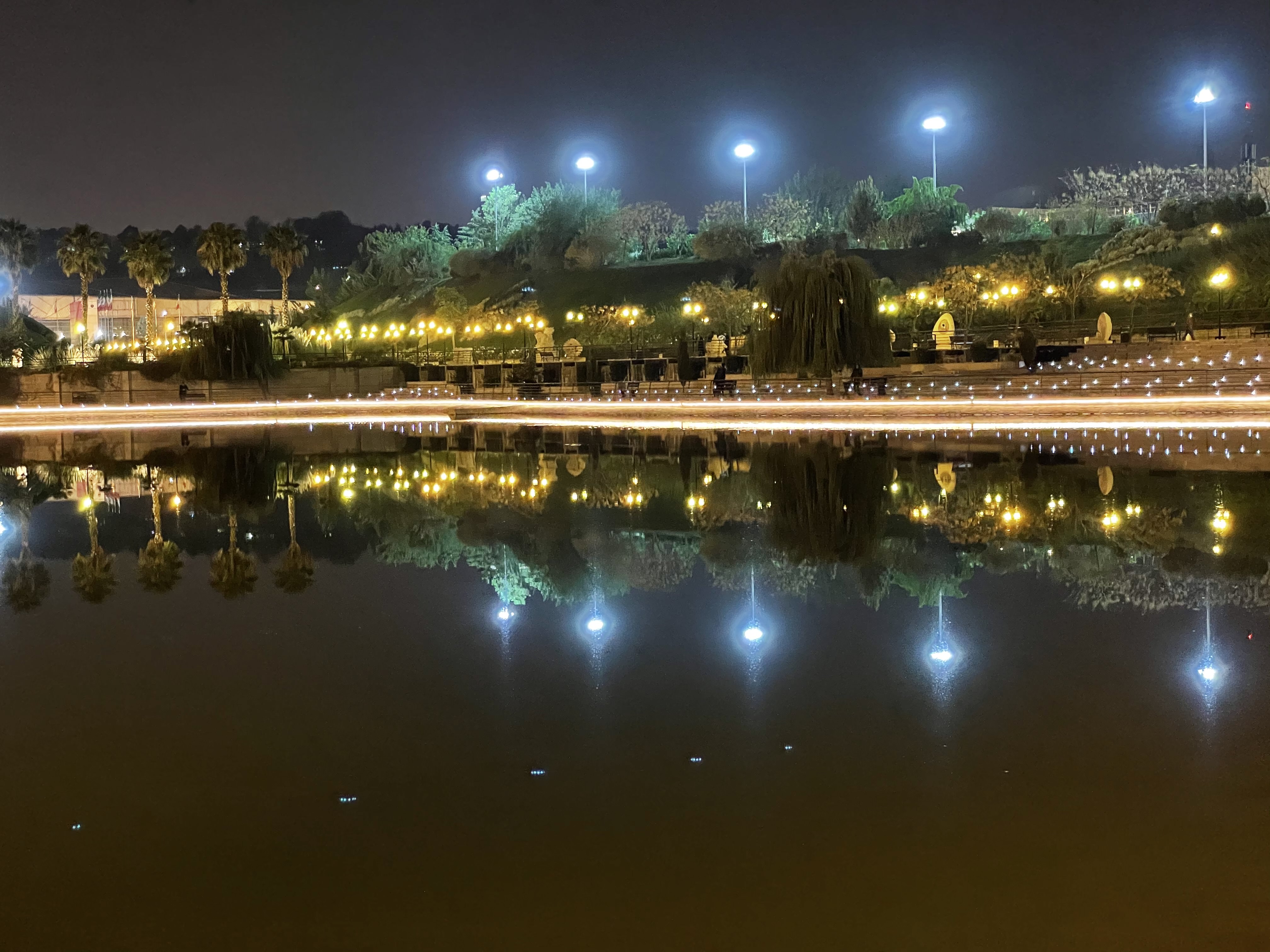 نمونه عکس دوربین تله فوتو آیفون ۱۲ پرو اپل در تاریکی - چراغانی کنار دریاچه ای در باغ کتاب تهران