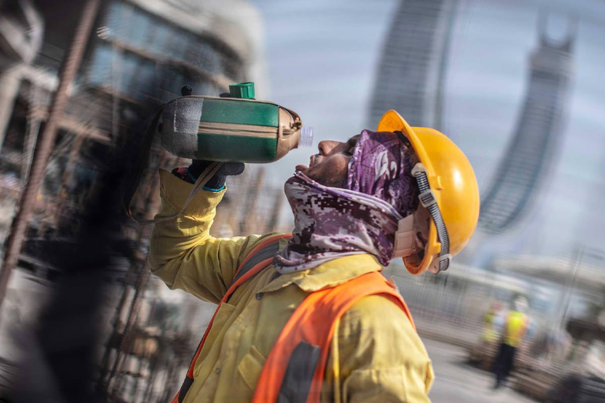 کارگر قطری در حال آب خوردن در گرمای جام جهانی
