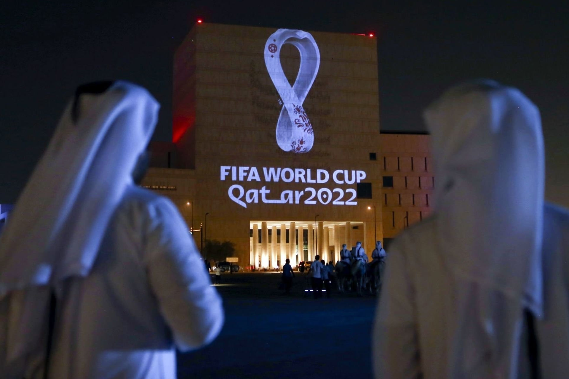 دو مرد قطری در حال نگاه به بنر جام جهانی ۲۰۲۲ فوتبال