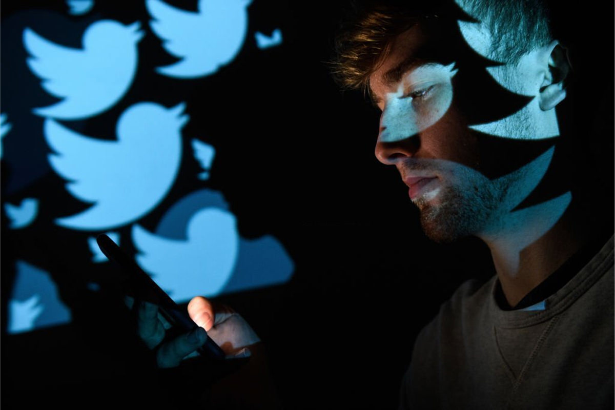 مرد جوان در حال استفاده از شبکه اجتماعی توییتر / توییتر روی گوشی
